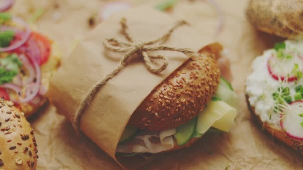 Bagels con jamón, queso crema, hummus, rábano envuelto en papel de hornear marrón listo para llevar — Vídeos de Stock
