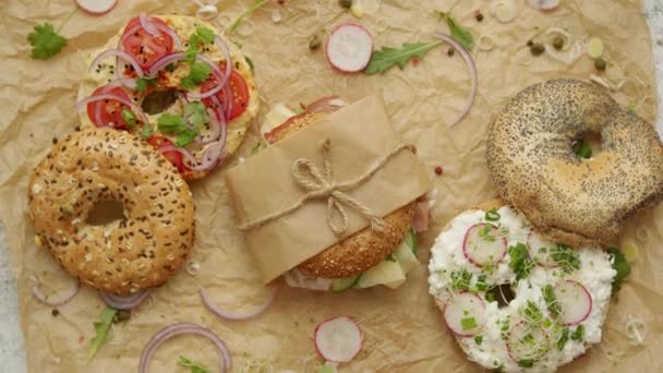 Bagels com presunto, queijo creme, húmus, rabanete embrulhado em papel manteiga marrom pronto para levar — Vídeo de Stock