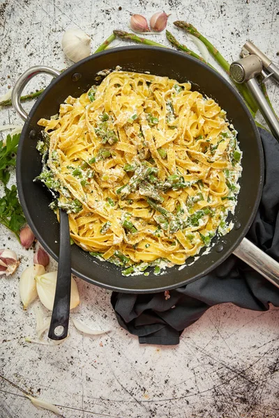 Pâtes tagliatelles maison avec sauce crémeuse au fromage ricotta et asperges fraîches servies sur une casserole en fer — Photo