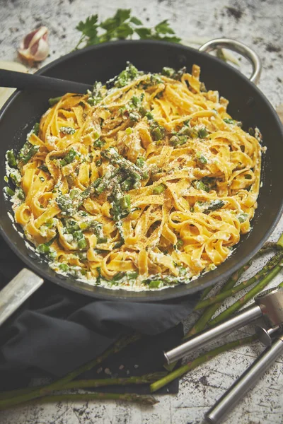 Pasta de tagliatelle con salsa de queso ricotta y espárragos servidos en una sartén de hierro negro —  Fotos de Stock