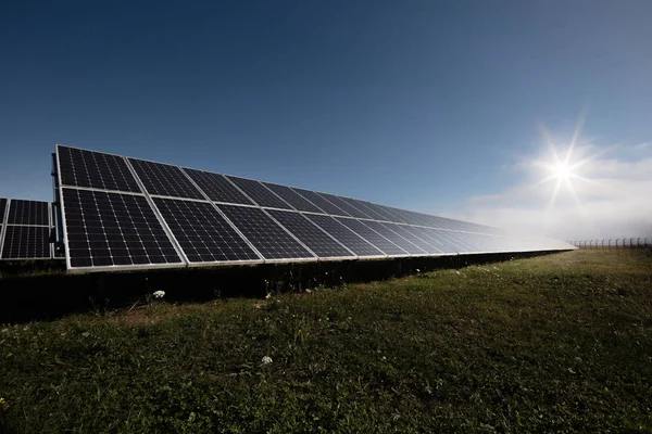 Impianto fotovoltaico con luce solare e nuvole sullo schienale — Foto Stock