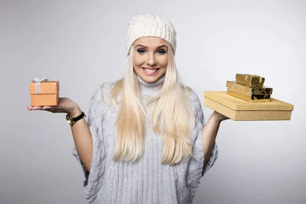 Mulher alegre segurando caixas de presente com presentes em um fundo cinza — Fotografia de Stock