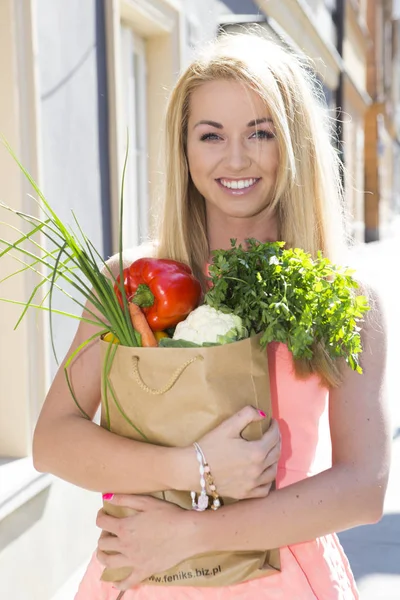 Junge Frau mit einer Einkaufstasche. Gemüse Stockbild