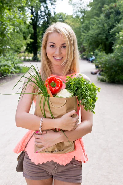 Junge Frau mit einer Einkaufstasche. Gemüse lizenzfreie Stockfotos