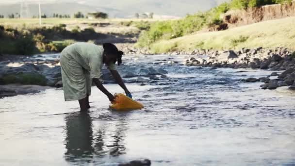 Африканская женщина получает воду из реки — стоковое видео