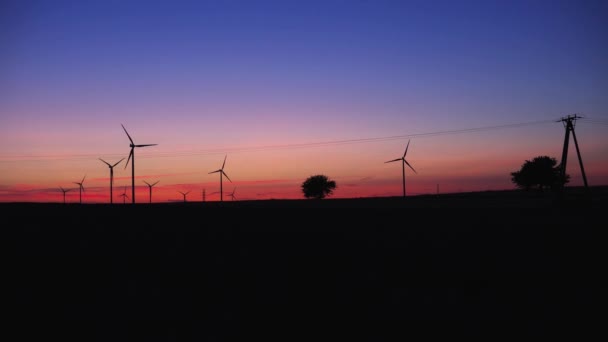 Устойчивый Снимок Силуэта Полевыми Ветровыми Турбинами Над Красным Голубым Небом — стоковое видео
