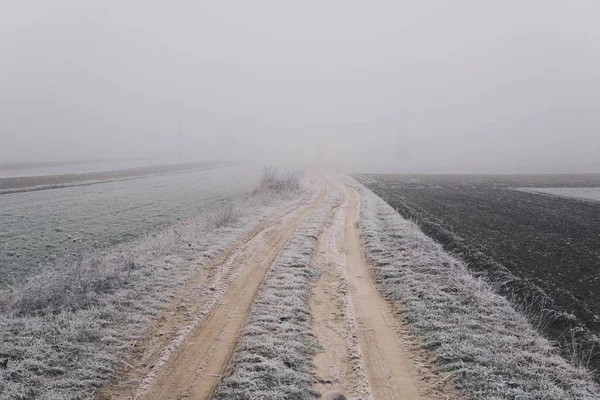 Camino de tierra a través de un campo que desaparece en una niebla — Foto de Stock