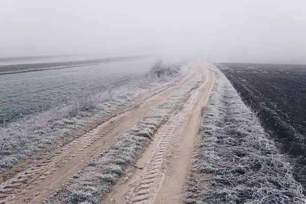 Ground road through a fields disappearing in a fog — Stock Photo, Image