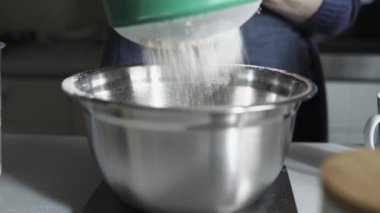 Ev mutfağında metal bir kâseye buğday unu süzme ayrıntıları. 