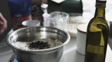 Ev mutfağı manzarasında metal bir kasenin içinde beyaz unla balkabağı tohumlarını karıştırmak. 