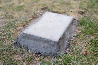 çimlerle çevrili bir zemine gömülü beton blok