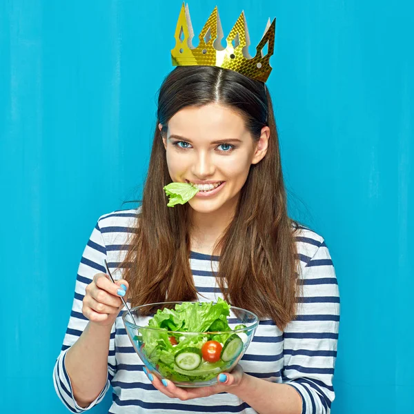 Leende flicka bära krona äta sallad. — Stockfoto