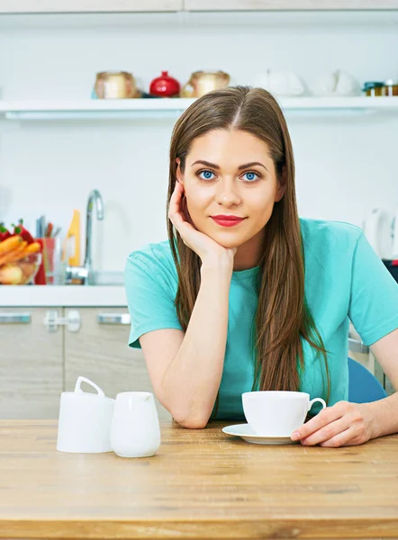 Vrouw zit aan keuken met koffiekopje. — Stockfoto