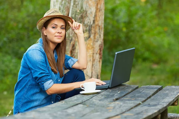 Homework in garden with laptop and coffee cup.