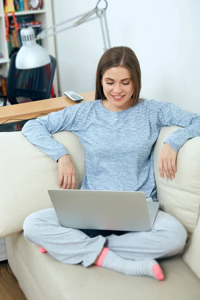 Giovane donna seduta sul divano con computer portatile . — Foto Stock