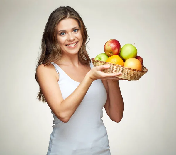 Mulher sorridente segurando cesta de palha com frutas . — Fotografia de Stock