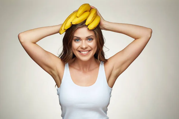 Mujer sonriente sosteniendo plátano en la cabeza . — Foto de Stock