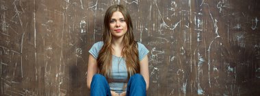 Uzun saçlı bir yere oturmak rahat giyimli kadın.