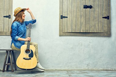 Sokak bankta oturan gitar ile gülümseyen kadın 