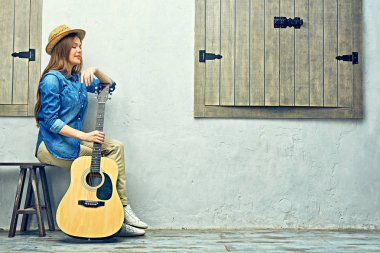Gitarla bankta oturan Womann.