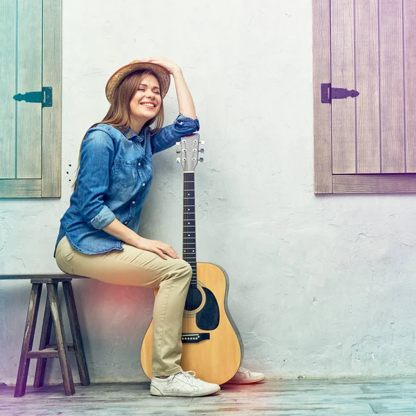 Womann sitter på bänken med gitarr. — Stockfoto