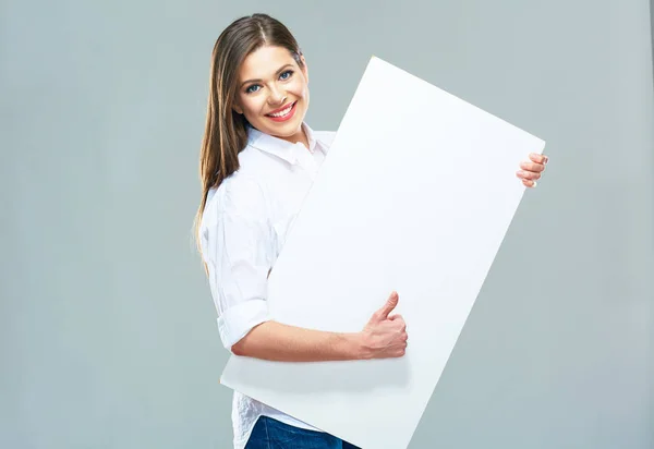 Femme souriante debout derrière panneau blanc vierge et montrer t — Photo