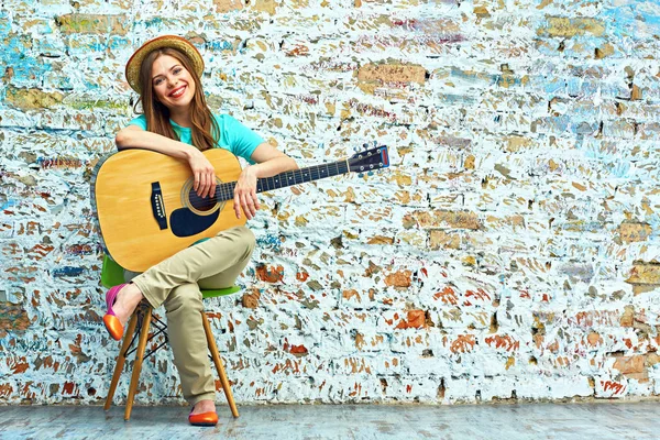 Lachende jonge vrouw die zit met gitaar — Stockfoto