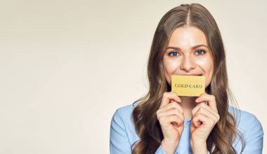 Gold kart tutan gülümseyen genç kadın. 
