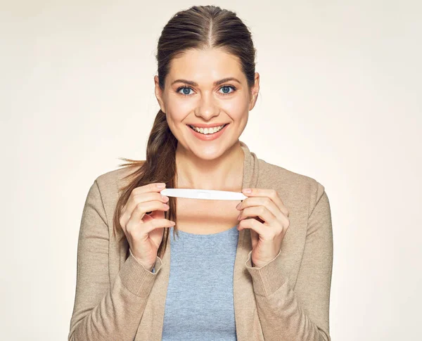 Portrait isolé d'une jeune femme souriante tenant un test de grossesse . — Photo