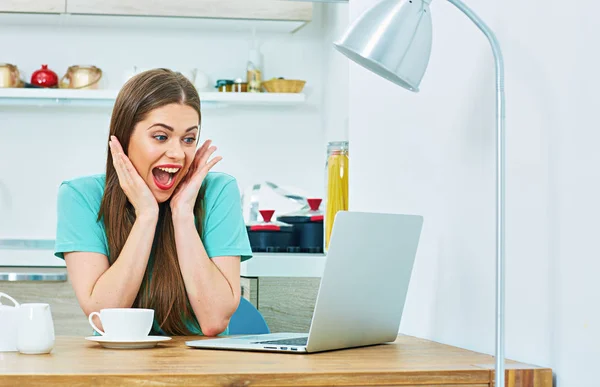 Surprising woman with laptop sitting in kitchen. — Stock Photo, Image