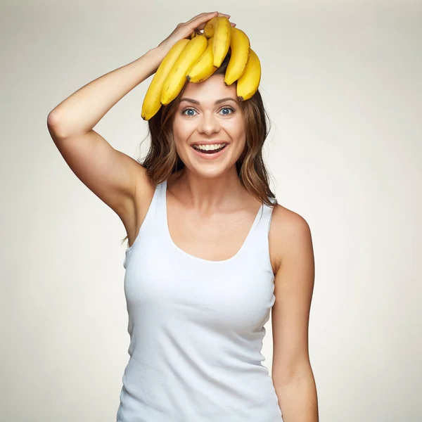 Mujer sonriente sosteniendo plátano en la cabeza . — Foto de Stock