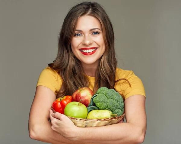 Молодая улыбающаяся женщина держит соломенную корзину с фруктами и овощами — стоковое фото