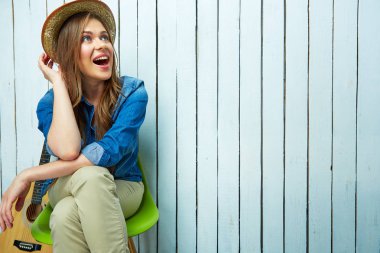 Gülümseyen genç kadın gitar ile oturuyordu