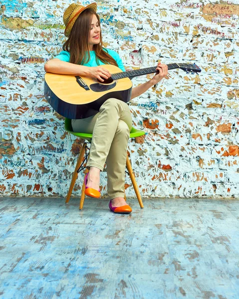 Kvinna sitter på stol och spela gitarr — Stockfoto