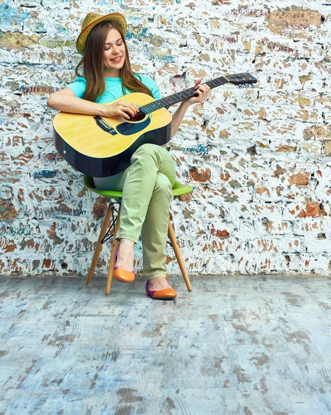 Kobieta siedzi na fotelu i gra na gitarze — Zdjęcie stockowe
