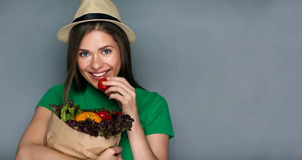 Ung kvinna som håller papperspåse med grönsaker — Stockfoto