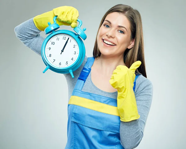 Smiling woman wearing builder overall holding alarm clock — Stock Photo, Image