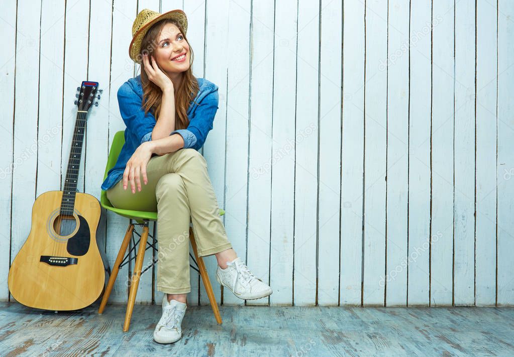 Smiling young woman sitting with guitar