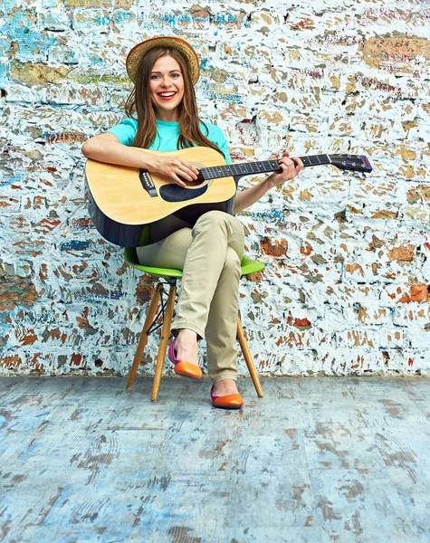 Frau sitzt auf Stuhl und spielt Gitarre — Stockfoto