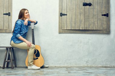 Gitar ile sokakta oturan genç kadın.