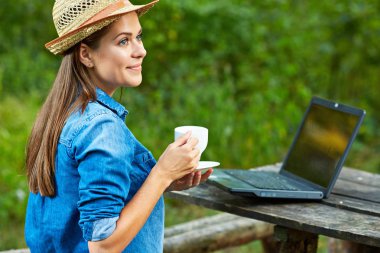  bahçede kahve içme ve laptop ile çalışan kadın.