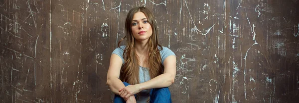 Uzun saçlı bir yere oturmak rahat giyimli kadın.