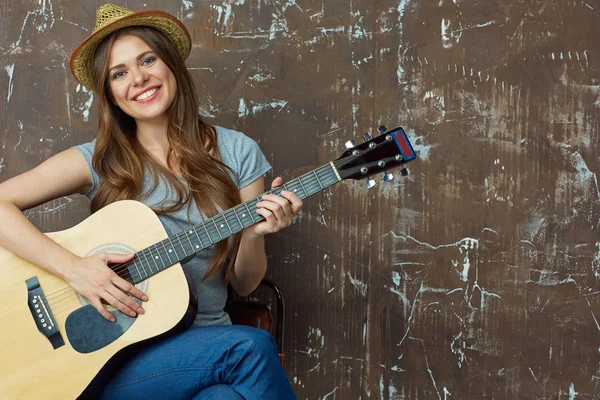 Felice giovane donna con cappello seduta con chitarra acustica su grun — Foto Stock