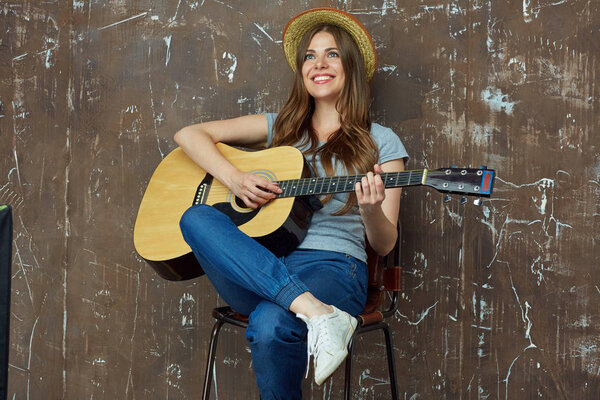 Smiling young woman portrait with acoustic guitar.