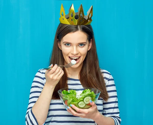 Leende flicka bära krona äta sallad. — Stockfoto