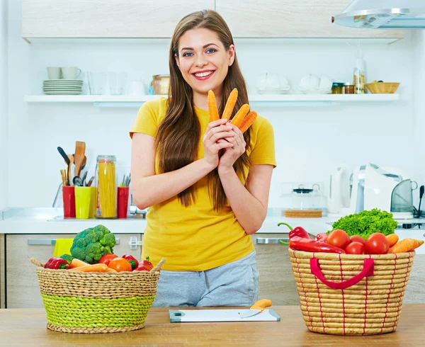 Lachende vrouw eten wortel in keuken. — Stockfoto