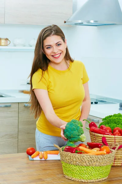 Mujer en cocina cocinando verduras. sonriente joven mujer —  Fotos de Stock