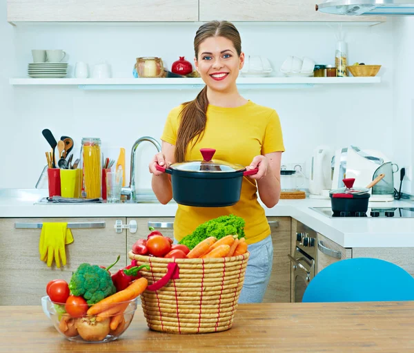 Usmívající se žena v kuchyni drží pánev. — Stock fotografie