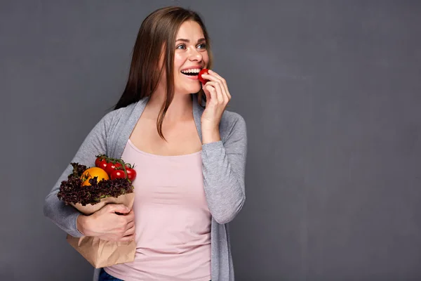 Vrouw met papieren zak met groenten eten van tomaat. — Stockfoto