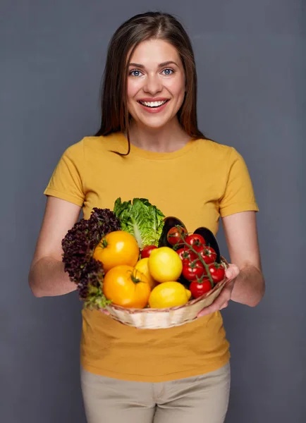 Smiling girl holding basket with summer vegetables. — Stock Photo, Image